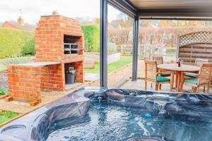 a hot tub in a patio with a brick oven at Cottage with Hot Tub - near Cheltenham and Tewkesbury in Cheltenham