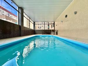 a swimming pool with blue water in a building at Apartamento com vista para o mar in Capão da Canoa