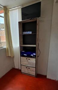 a book shelf with a tv on top of it at Alojamiento en Puno in Puno