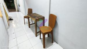 a table and two chairs sitting next to a wall at New Jasmine Guest House by Yurooms in Karangtengah