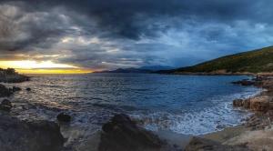 a sunset over a body of water with rocks at Villa Symphony apartments Kotor Tivat in Kotor