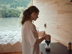 Eine Frau steht mit einer Tasse vor einem Tisch. in der Unterkunft allbeans KOCHI in Kami