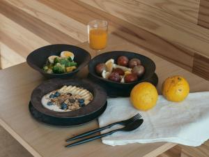 Drei Schüsseln mit Essen auf einem Tisch, dazu ein Glas Orangensaft in der Unterkunft allbeans KOCHI in Kami