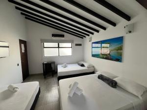 una stanza bianca con due letti e una finestra di Hotel Jardin de Laureles Jeps a Medellín