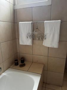 un bagno con asciugamani bianchi su un supporto e una vasca di Dior-X Manor a Durban Altre 6 foto