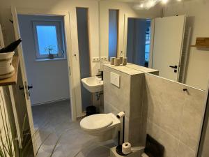 a white bathroom with a toilet and a sink at Traumhafte Ferienwohnung zwischen Ostsee und Hansestadt in Stockelsdorf +21 photos