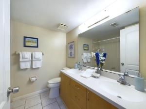 a bathroom with a sink and a toilet and a mirror at Sandcastles 2br2ba Cocoa Beach Ocean Views! in Cocoa Beach