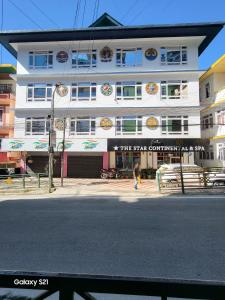 a white building with a woman walking in front of it at The Star Continental & Spa Gangtok in Gangtok