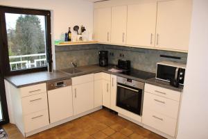 Una cocina con gabinetes blancos y un fregadero y una ventana. en FeWo Oberhausen-Styrum, en Oberhausen