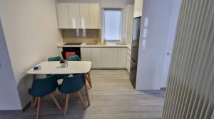 a kitchen with a white table and blue chairs at myHome Residence in Nazna