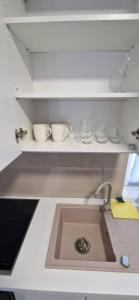 a kitchen counter with a sink and bowls on a shelf at myHome Residence in Nazna +5 photos