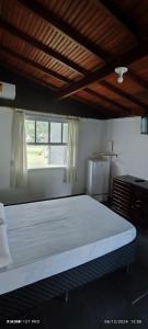 a large white bed in a room with a window at Chales Mata Atlantica De Ubatuba in Ubatuba