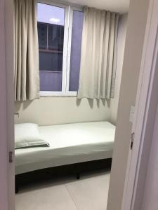 Una cama pequeña en una habitación con ventana. en Cobertura frente mar 2 suítes, en Itapema