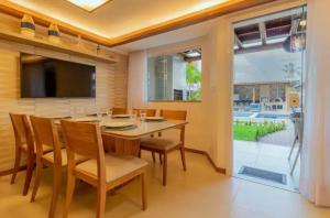 a dining room with a table and chairs and a television at Casa Itacimitim Praia do Surf in Camacari