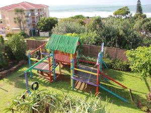 a colorful playground in a yard with the ocean in the background at #17 Illovo Views in Kingsburgh