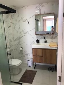 Un baño con inodoro, lavabo y espejo. en Cobertura frente mar 2 suítes, en Itapema