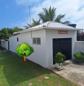 una casa bianca con un garage con un albero in cortile di Bangalô MAR & SOL a Saquarema