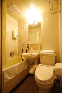 a bathroom with a toilet and a sink and a mirror at Sunsky Hotel in Kitakyushu