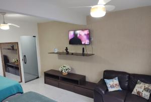 a living room with a couch and a tv on the wall at Bangalô MAR & SOL in Saquarema