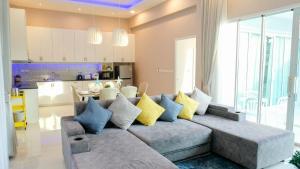 a living room with a gray couch with colorful pillows at Fin Camping & Pool Villa in Ban Hup Kaphong