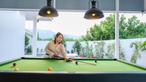 een vrouw die pool speelt op een pooltafel bij Fin Camping & Pool Villa in Ban Hup Kaphong