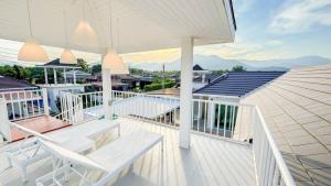 een wit terras met twee witte stoelen en een zwembad bij Fin Camping & Pool Villa in Ban Hup Kaphong