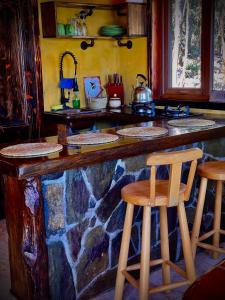a kitchen with a stone counter with two bar stools at Cozzy Cabin at "Explore-Cafe & Lodge" Located in Duhatao, Chiloe Island, Patagonia, Chile in Ancud +23 photos