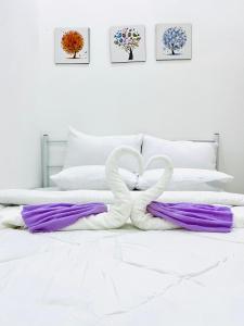 a white bed with purple and white pillows at Syapins Cozy Haven Homestay Musslim Only in Lunas