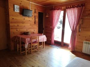 a dining room with a table and a tv at La Cabane d'Oza in Saint-Pierre-dels-Forcats
