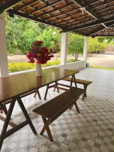 a wooden bench with a vase of flowers on a patio at Sítio Caju in Aquiraz