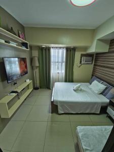 a hotel room with a bed and a television at Cozy Condo in the City Center at Horizons 101 in Cebu City