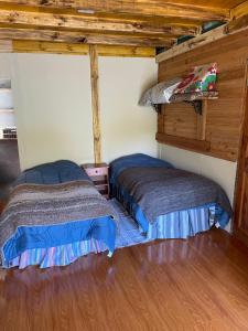 Dos camas en una habitación con techos de madera. en Lodge Casa de Campo, en Futaleufú