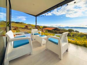 a patio with white chairs and a view of the ocean at Cabañas en el Lago Calima in Calima +21 photos