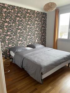 a bedroom with a bed with a floral accent wall at La Villa Sénéchal in Guérande +27 photos