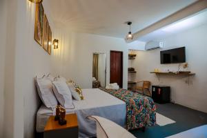 a hotel room with a bed and a tv at Aroeira Pousada in Trancoso