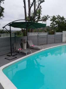 een zwembad met twee stoelen en een parasol bij 54 Malcolm Palace Room in Durban