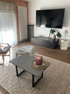 a living room with a table and a large tv at Ferienwohnung Uchtelfangen in Illingen