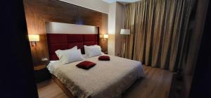a bedroom with a bed with two red pillows on it at Rin Grand Residence 1 in Bucharest +5 photos