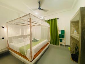 - une chambre avec un lit à baldaquin et un rideau vert dans l'établissement Bunty Villa Talalla, à Talalla South