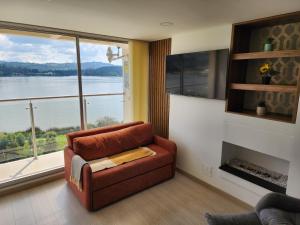 a living room with a couch and a large window at Increíble apartamento con vista panorámica al lago Sochagota in Paipa