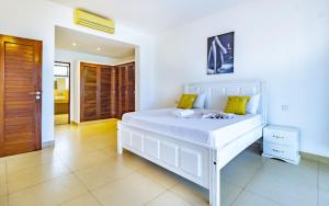 a white bed with yellow pillows in a bedroom at Luxury 3 bedroom beach front apartment in Mombasa