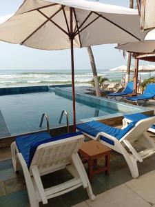 two chairs and an umbrella next to a swimming pool at Escape villa assouinde in Assinie