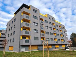 a gray building with yellow windows in a yard at Apartman JOLE in Velika Gorica