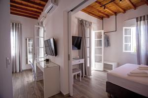 a bedroom with a bed and a desk with a television at C Suites Mykonos in Mikonos