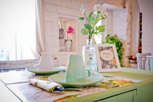 une table avec deux assiettes et un vase avec des fleurs dans l'établissement Casa Nonna Stella, à Martina Franca