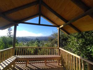 a wooden gazebo with a bench on a deck at Cabaña Loma Eco-sol in Molina