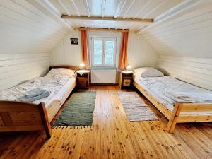 two beds in a room with wooden floors and a window at Haus Völlegg in Völlegg