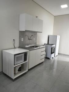 a kitchen with white cabinets and a sink and a refrigerator at Kitnet de 2 quartos no Jardim dos Ipês in Sorriso