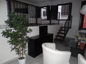 sala de estar con escalera y silla blanca en Málaga Apartamentos - Jinetes, 13, en Málaga
