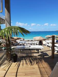 a beach with tables and umbrellas and the ocean at Zion Appartement SXM in Orient Bay